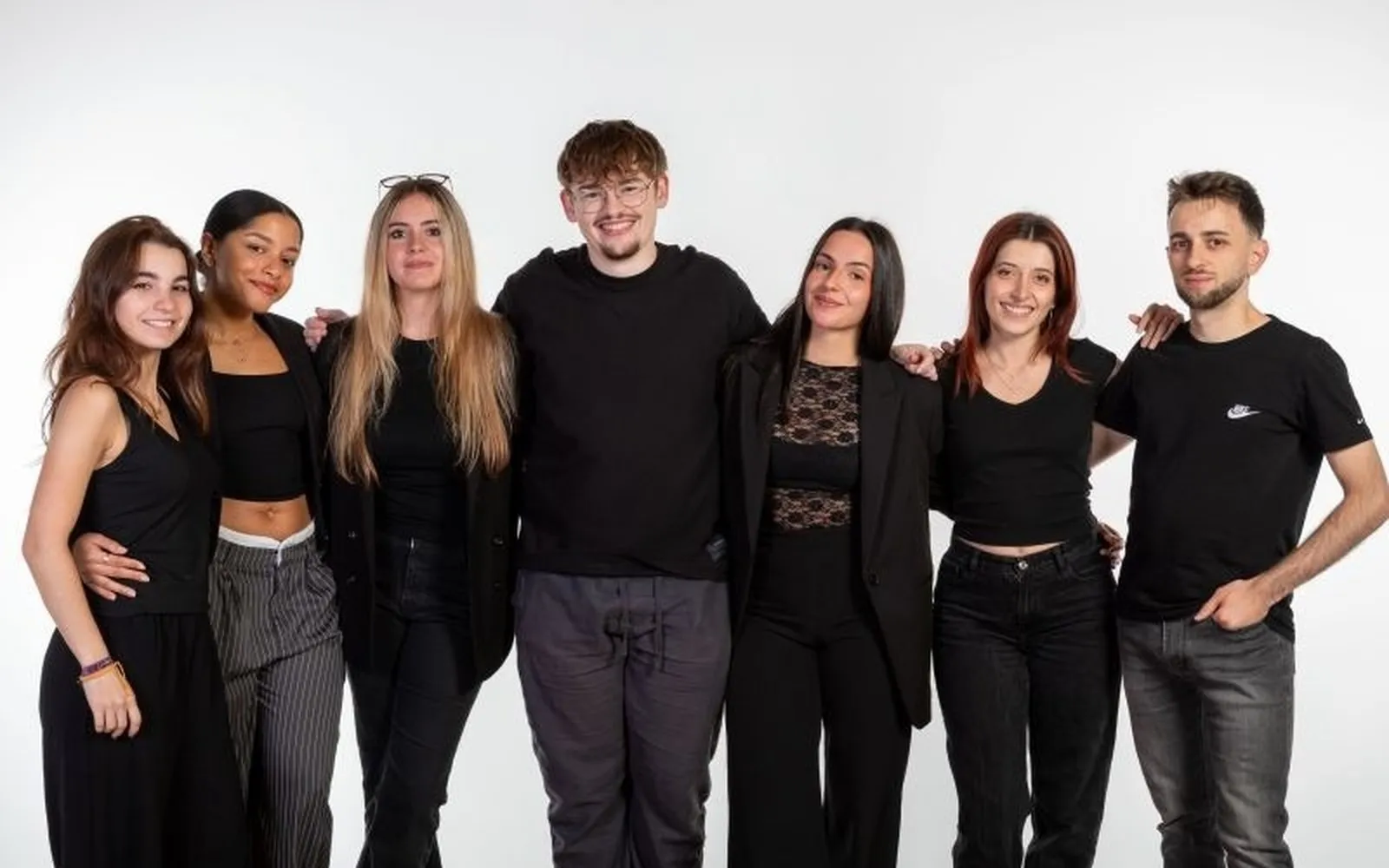 Gruppenfoto des Teams des Publicatessen Festivals vor weißem Hintergrund, sieben schwarz gekleidete Personen.